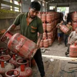 LPG CLYINDER PRICE HIKED DESPITE भारत में LPG सिलेंडर की कीमत बढ़ने के बाद गैस सिलेंडर लोड करता कर्मचारी